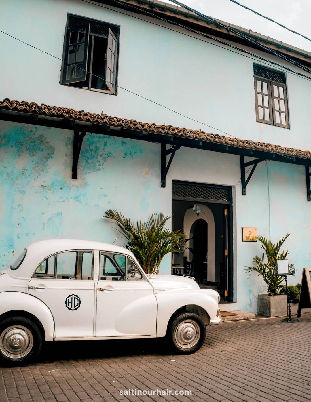 White vintage Morris Minor car parked outside the Heritage Galle Fort Hotel in Galle, Sri Lanka.