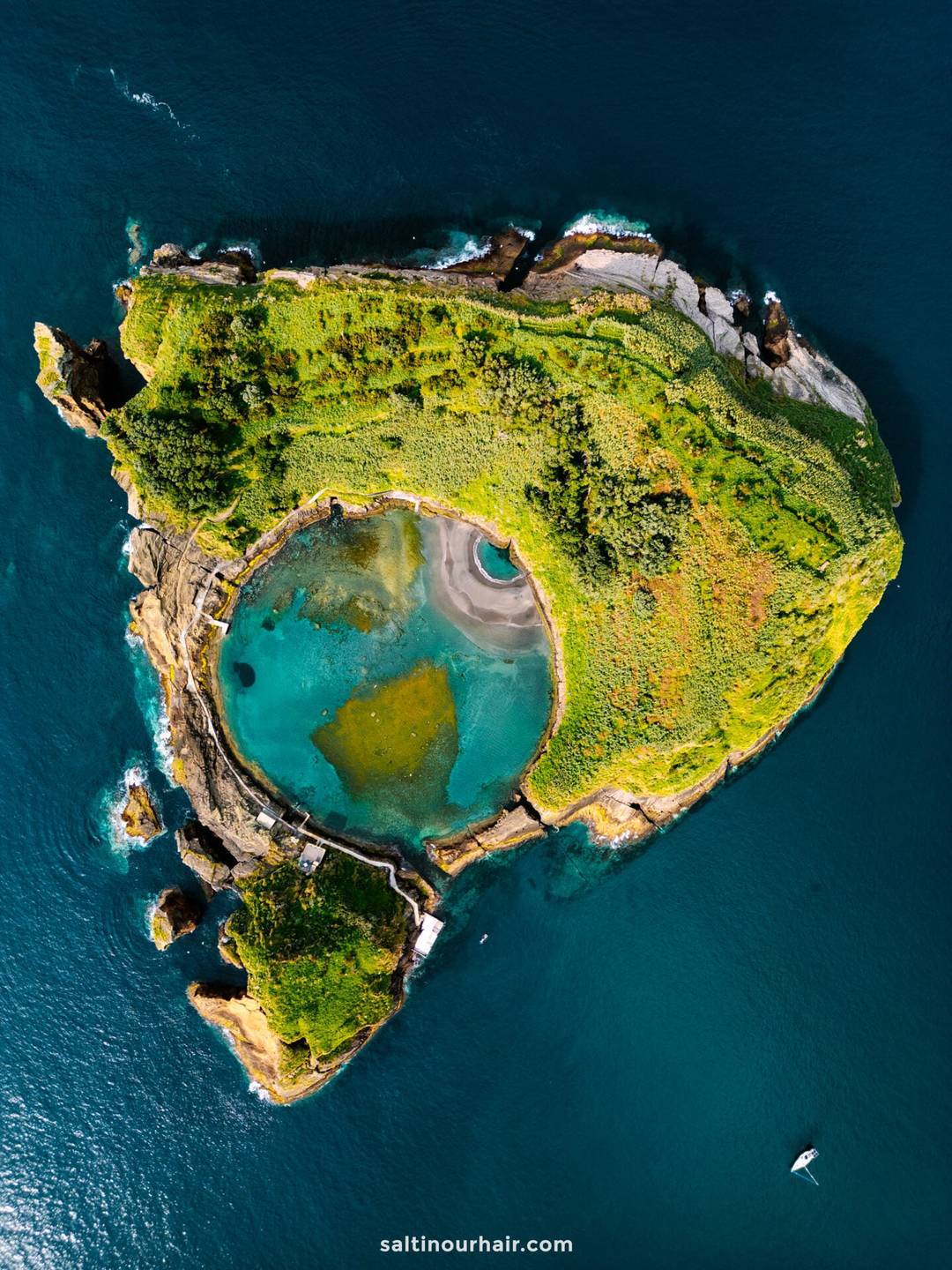 Aerial view of a small, green, heart-shaped island with a circular blue lagoon in the center, surrounded by deep blue ocean&mdash;one of the remarkable sights among the things to do in S&atilde;o Miguel, Azores.