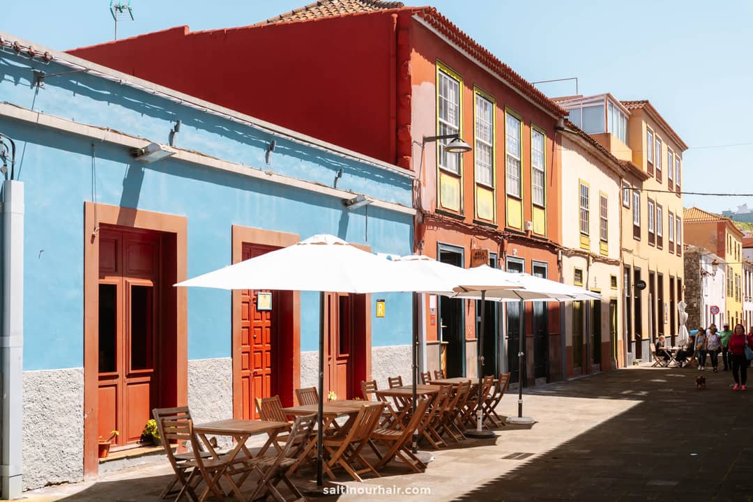Terrastafels met parasols langs een straat met kasseien voor kleurrijke gebouwen op een zonnige dag in San Crist&oacute;bal de La Laguna, Tenerife.