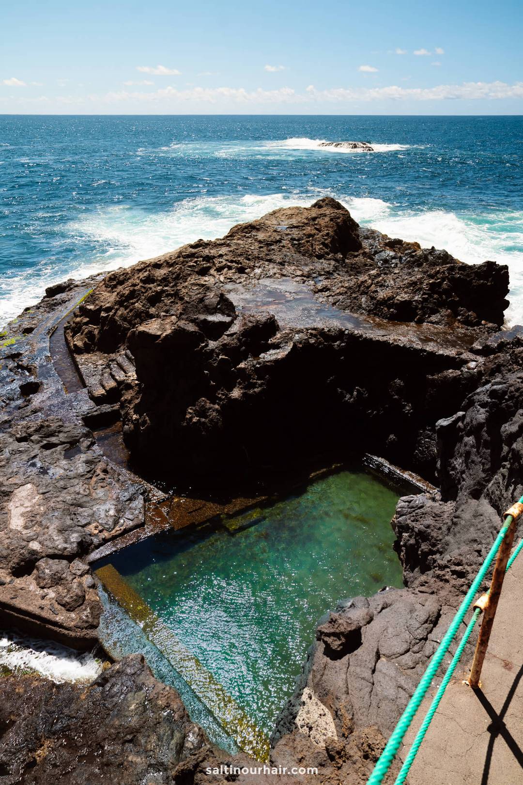 A natural ocean pool formed by rocks on the edge of the sea in La Palma, Canary Islands, with clear water and waves in the background under a blue sky&mdash;perfect for your next travel guide.