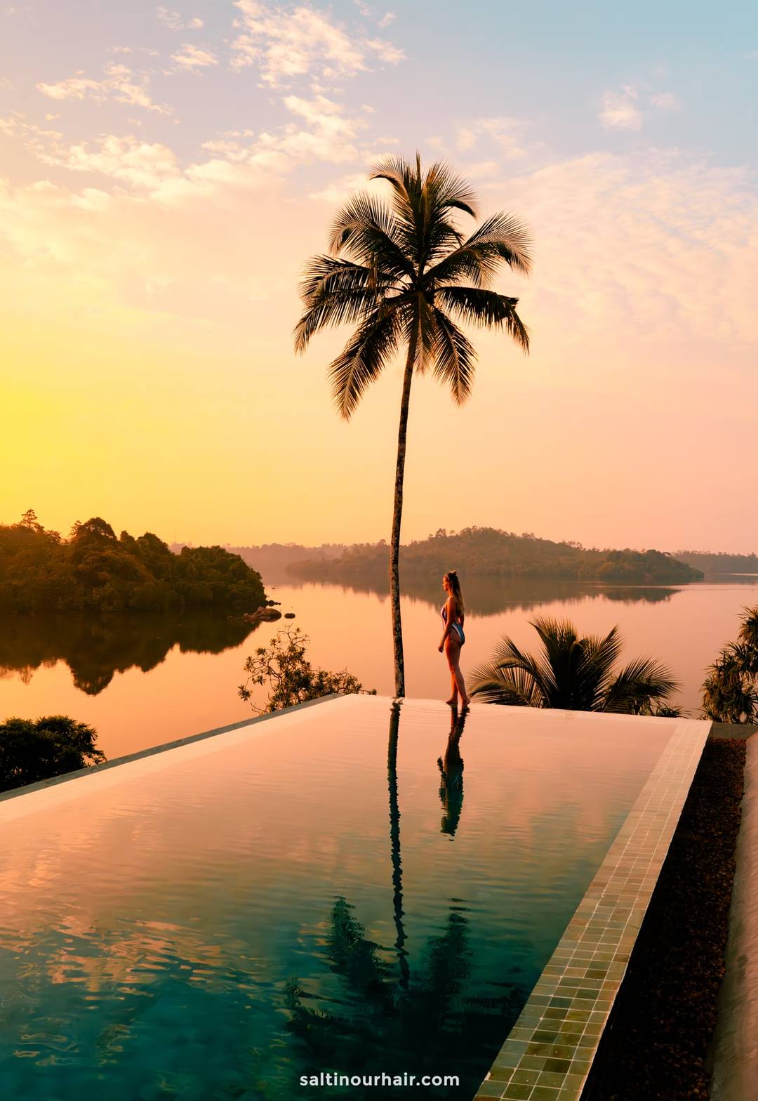 Woman in bikini standing at infinity pool edge overlooking Koggala Lake at sunset, Ahangama, Sri Lanka.