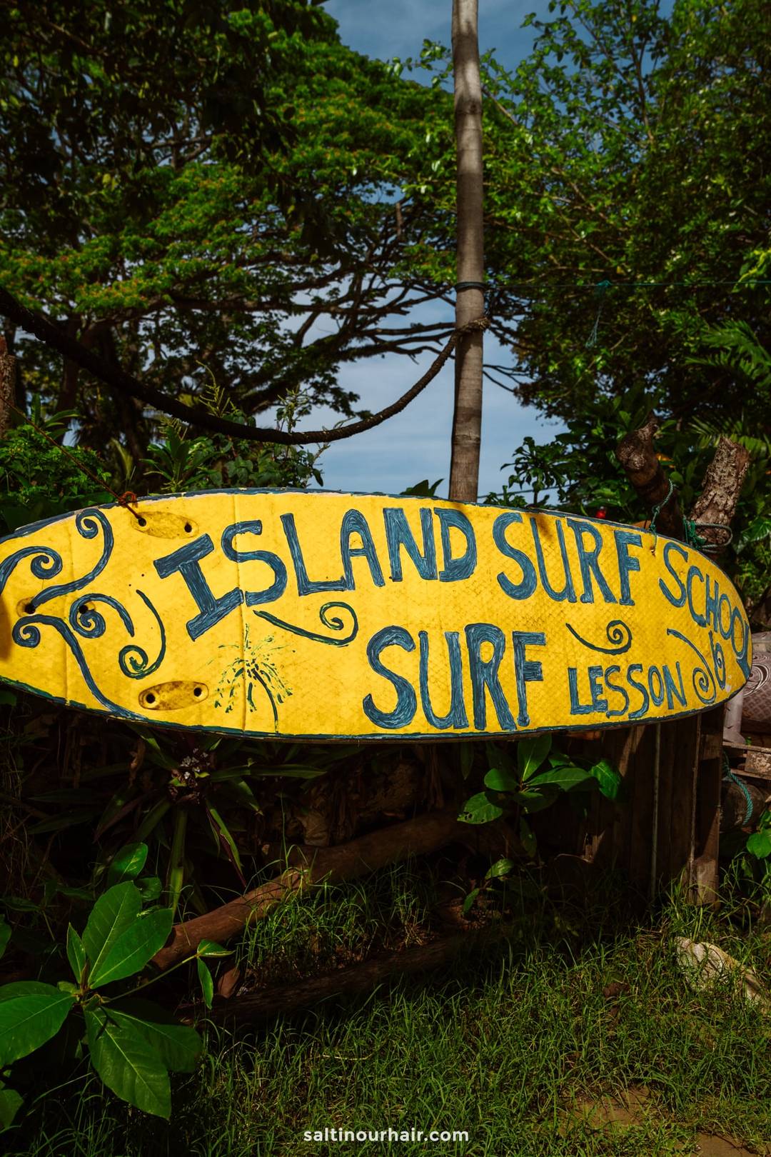 Yellow surfboard sign for Island Surf School offering surf lessons at Kabalana Beach in Ahangama, Sri Lanka.