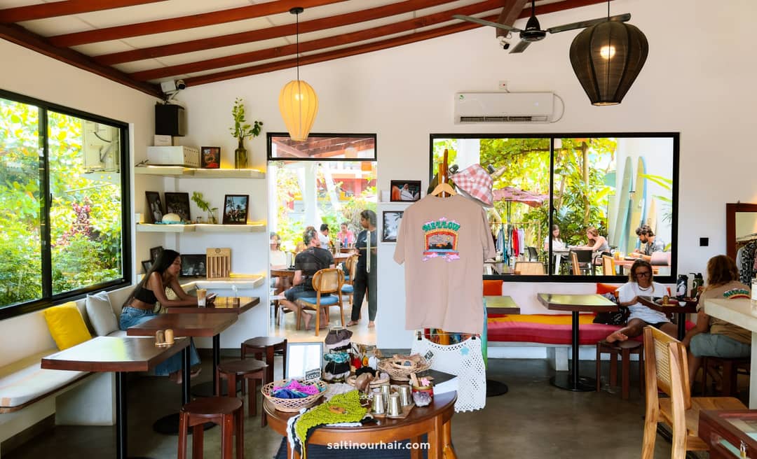 Interior of Mellow caf&eacute; in Ahangama with branded t-shirt display, rattan chairs, colorful bench seating, and guests dining.