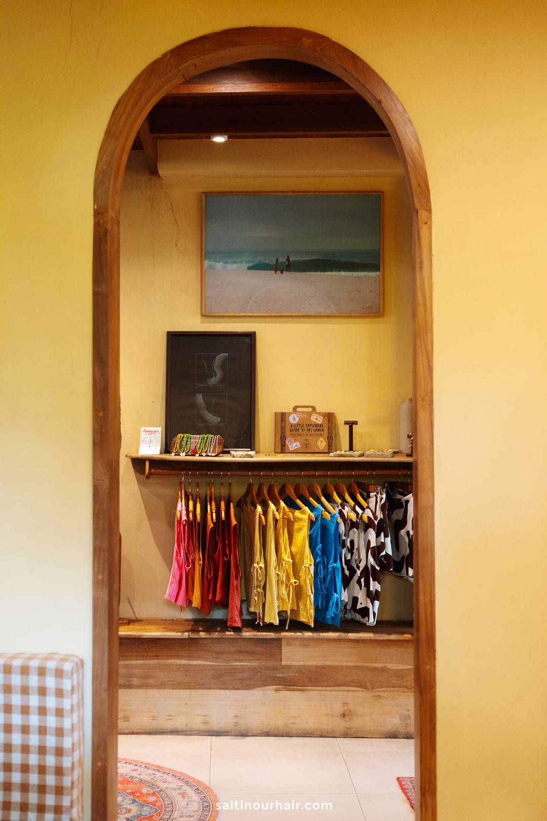 Colorful swimwear and resort clothing hanging on wooden racks inside a boutique shop in Ahangama, Sri Lanka.