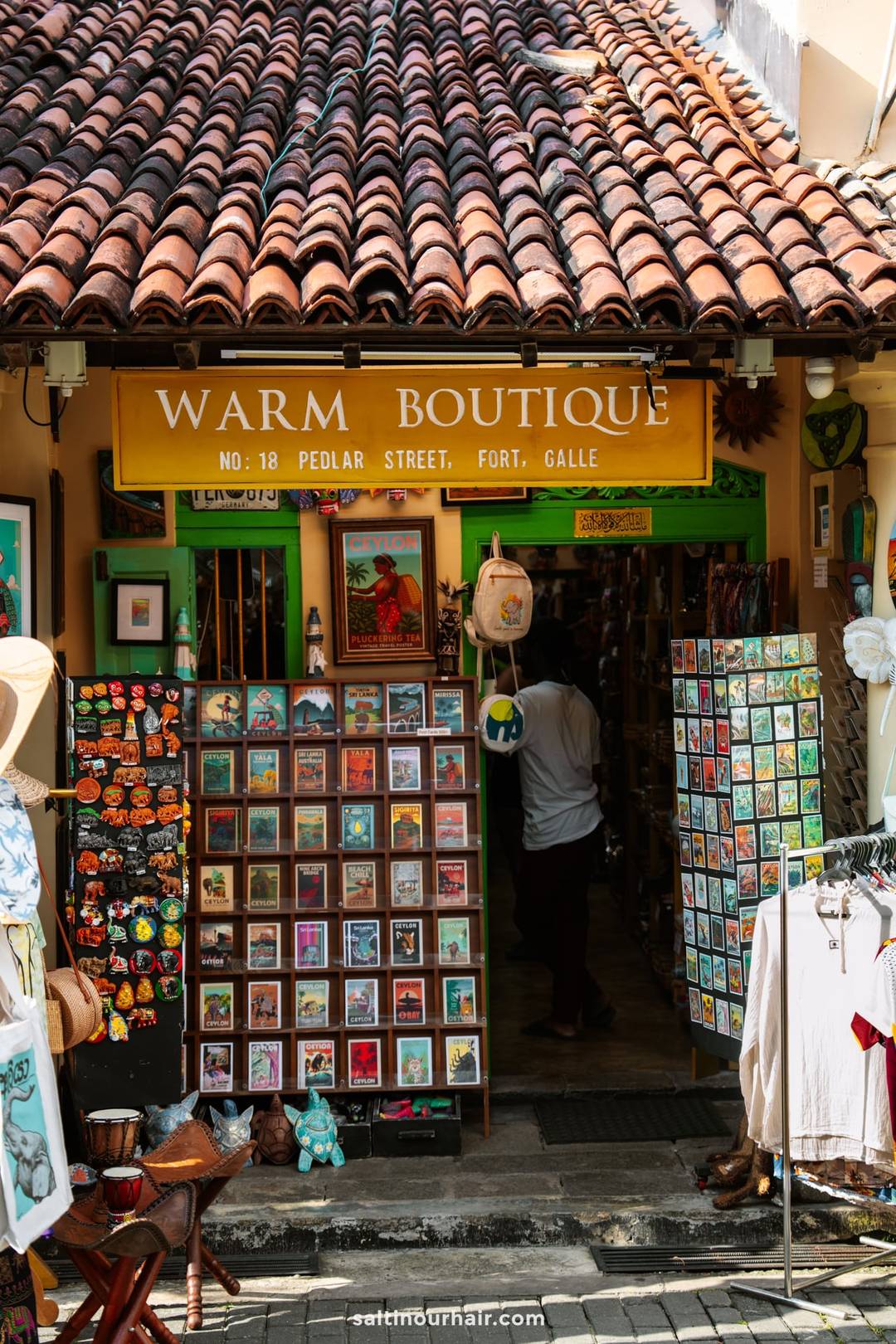 Warm Boutique souvenir shop on Pedlar Street in Galle Fort, Sri Lanka, displaying Ceylon postcards and magnets.