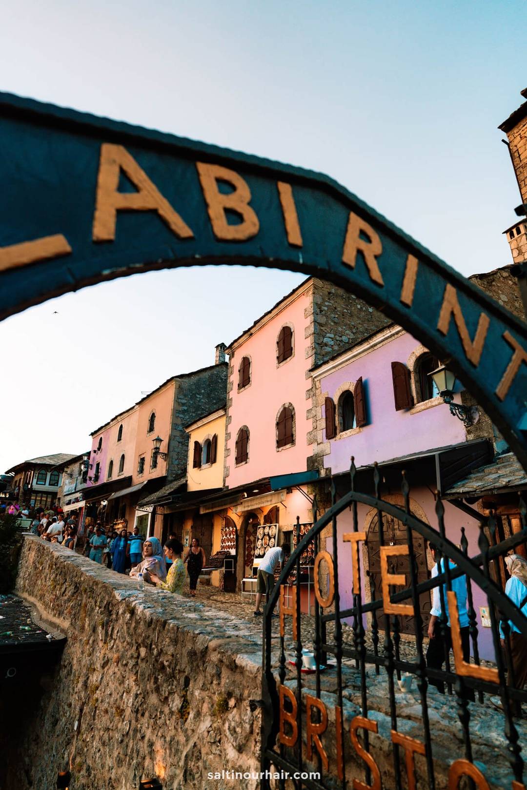 Labirint restaurant arch sign framing the colorful old bazaar street of Mostar, Bosnia, at golden hour.