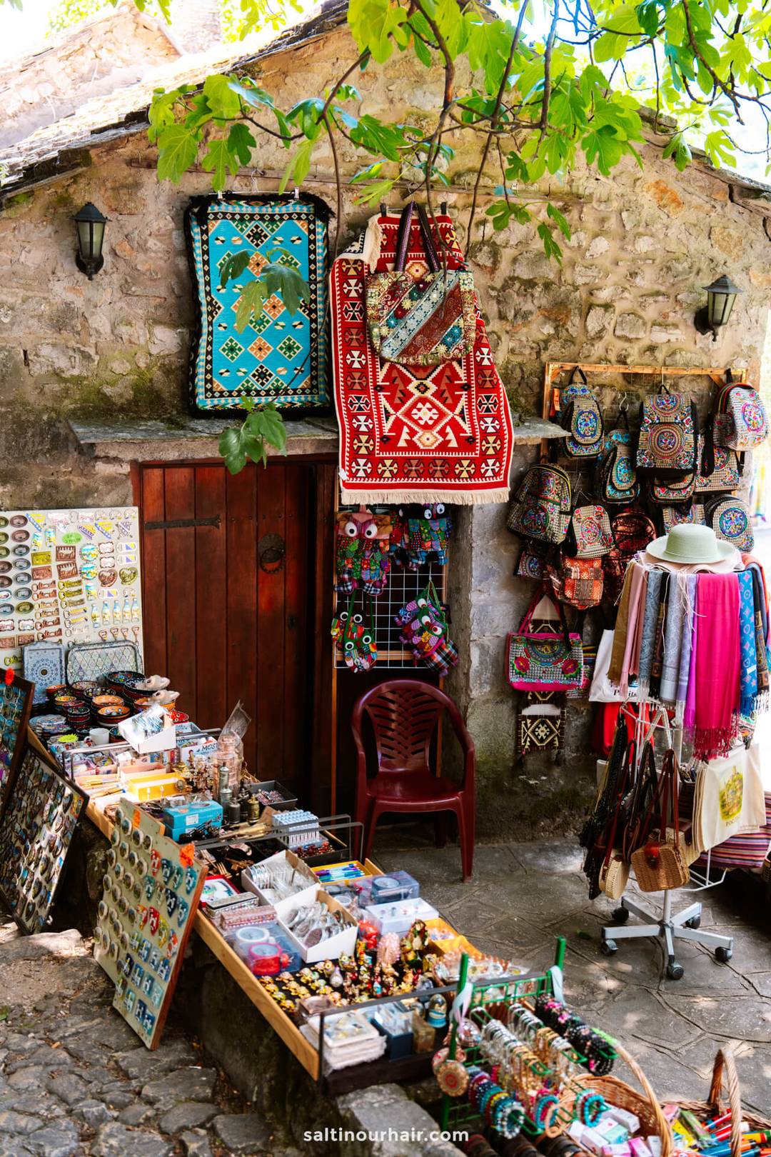Colorful souvenir stall with embroidered bags and kilim rugs at Počitelj Old Town, Bosnia and Herzegovina.