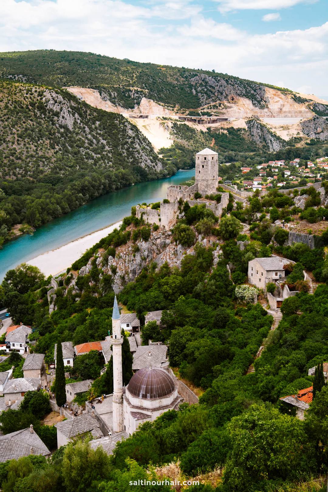 Aerial view of Počitelj Old Town in Bosnia, with its mosque, medieval tower, and the turquoise Neretva River below.